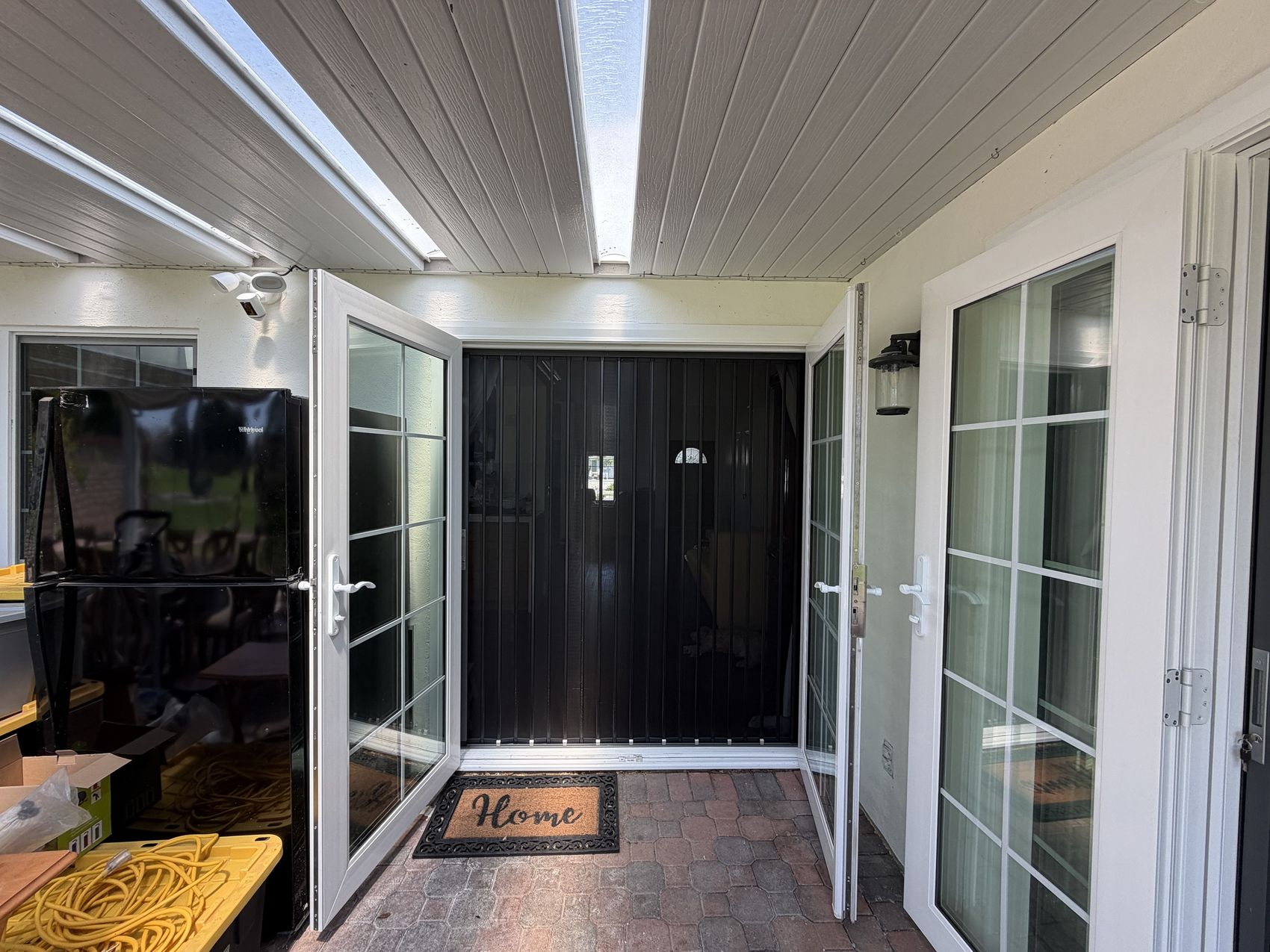 Black folding screen across a pair of open white French doors on a covered patio