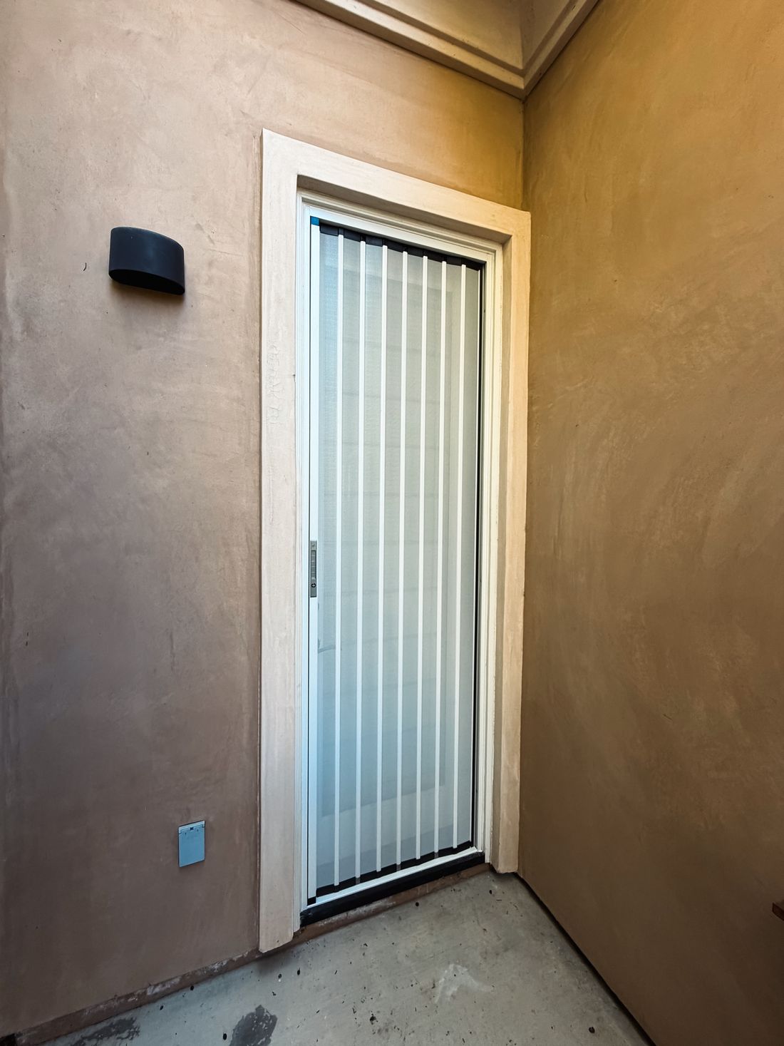 White folding screen on a single entry door in a stucco alcove